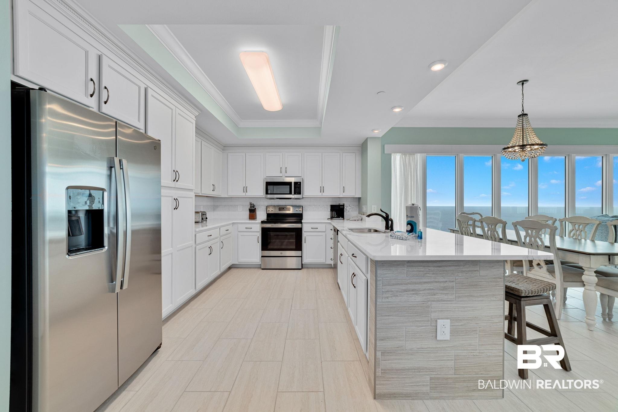 Image 3: Kitchen featuring white cabinetry, stainless steel appliances, and a tiled backsplash