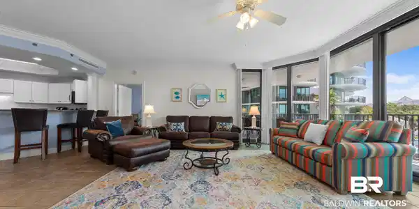 Image 2: Living area with ornamental molding, light tile patterned flooring, a textured ceiling, a ceiling fan, and a raised ceiling