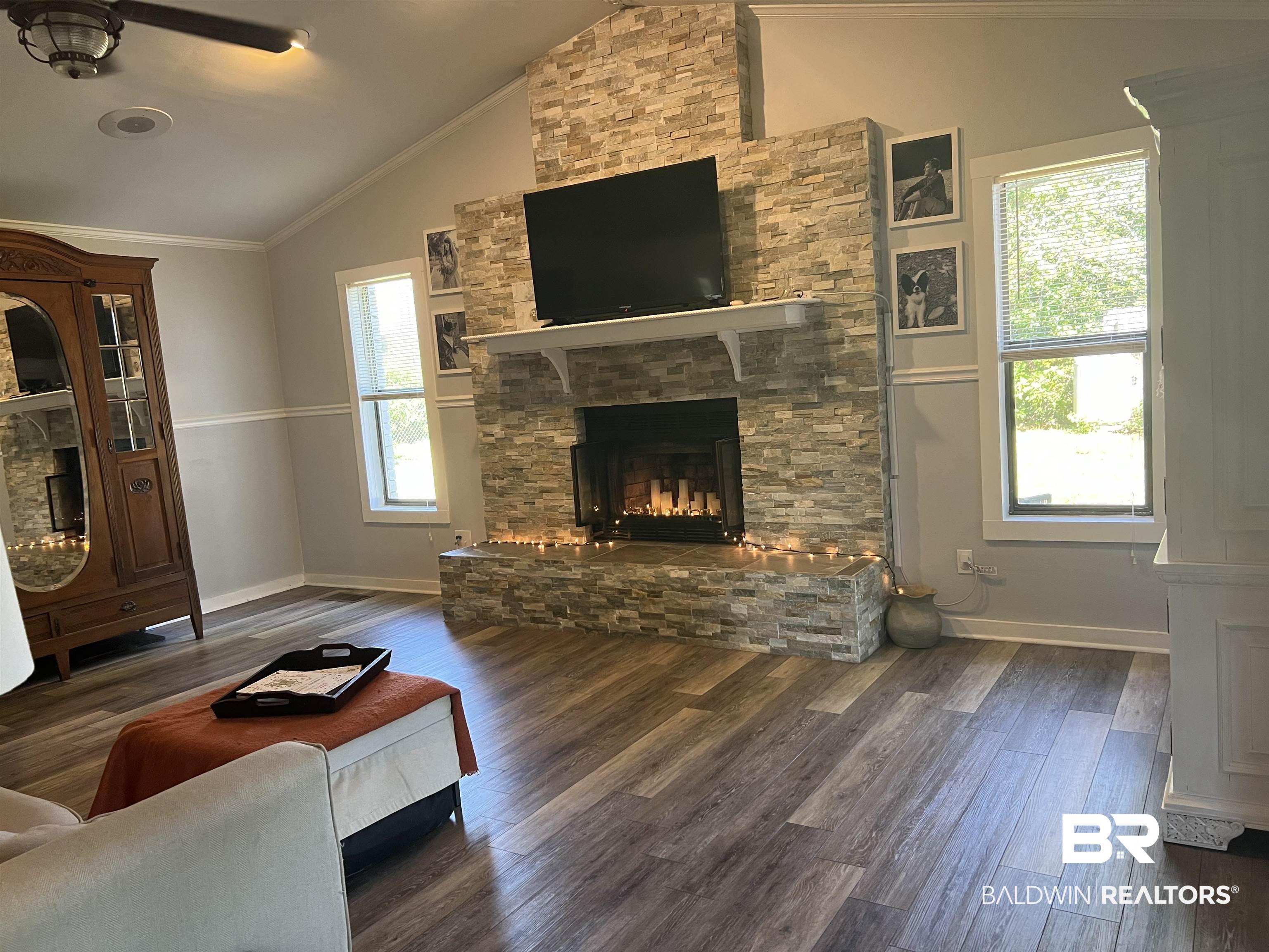 Image 3: Vaulted ceiling featuring a ceiling fan, stone-clad fireplace with mantel, wood-finish flooring, and recessed lighting