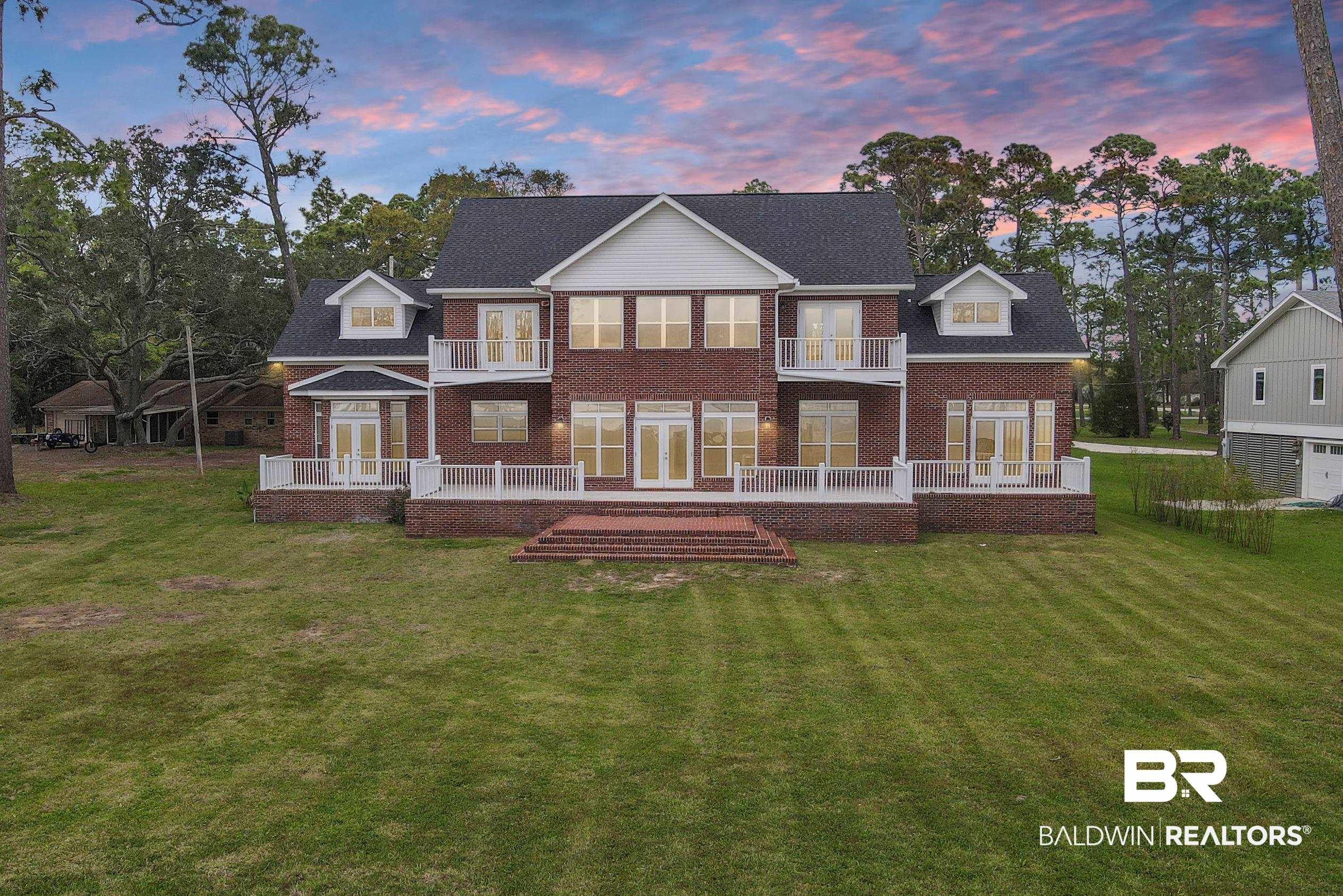 Image 2: Back house at dusk with a yard, a balcony, a deck, and french doors