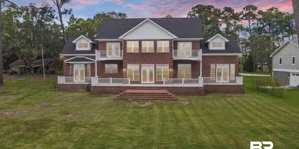 Image 2: Back house at dusk with a yard, a balcony, a deck, and french doors