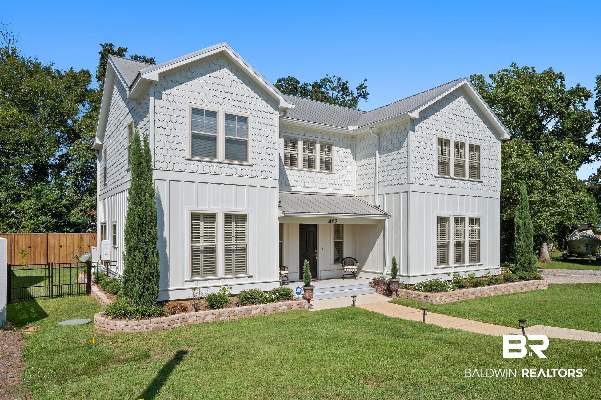 Image 1: View of front of house with board and batten siding, a metal roof, a porch, and freshly landscaped grounds