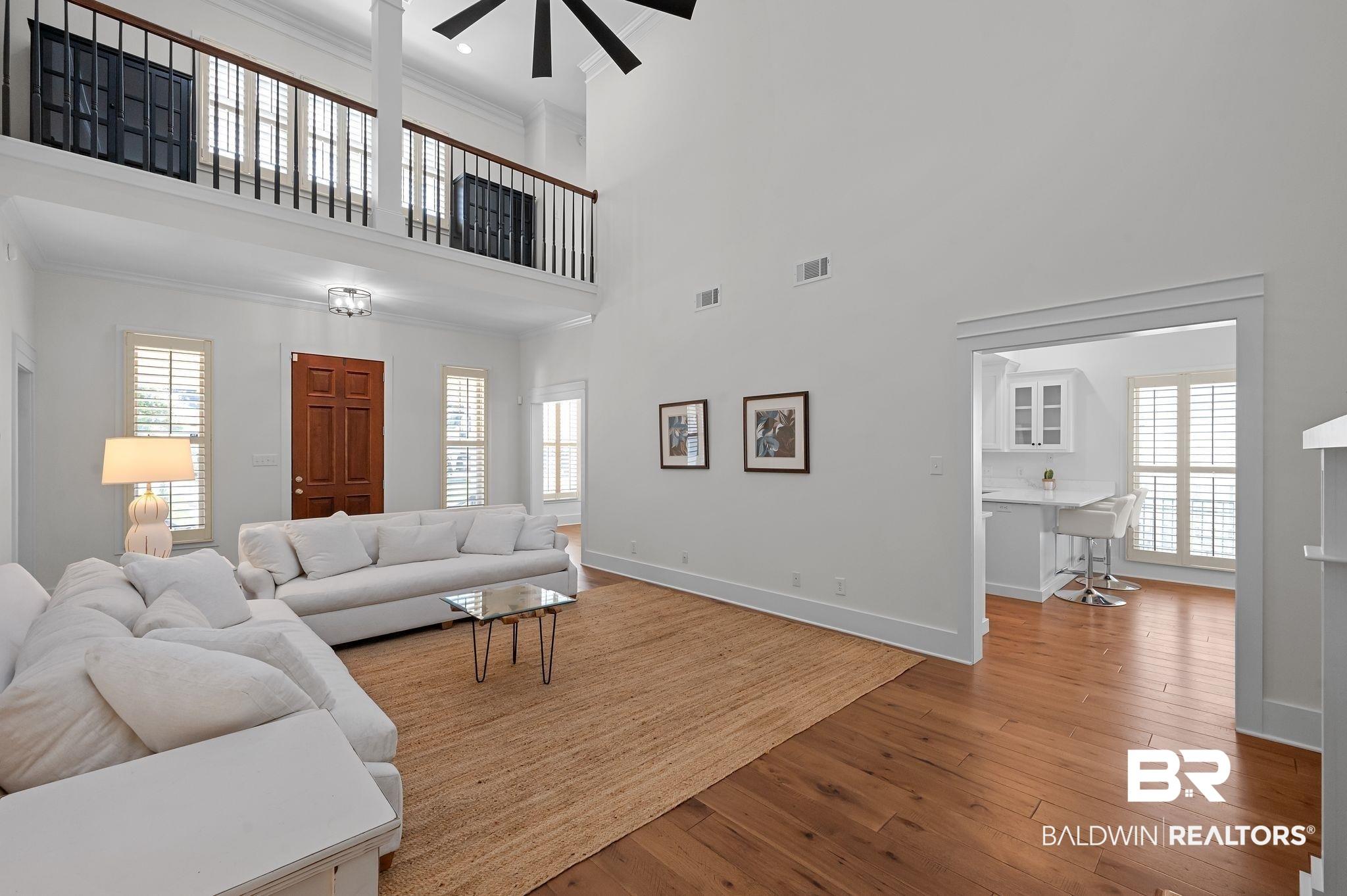 Image 2: Living room featuring hardwood / wood-style floors, ornamental molding, a high ceiling, and a ceiling fan