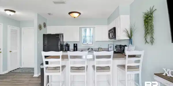 Image 3: Kitchen with a peninsula, a textured ceiling, wood finished floors, white cabinetry, and a kitchen breakfast bar