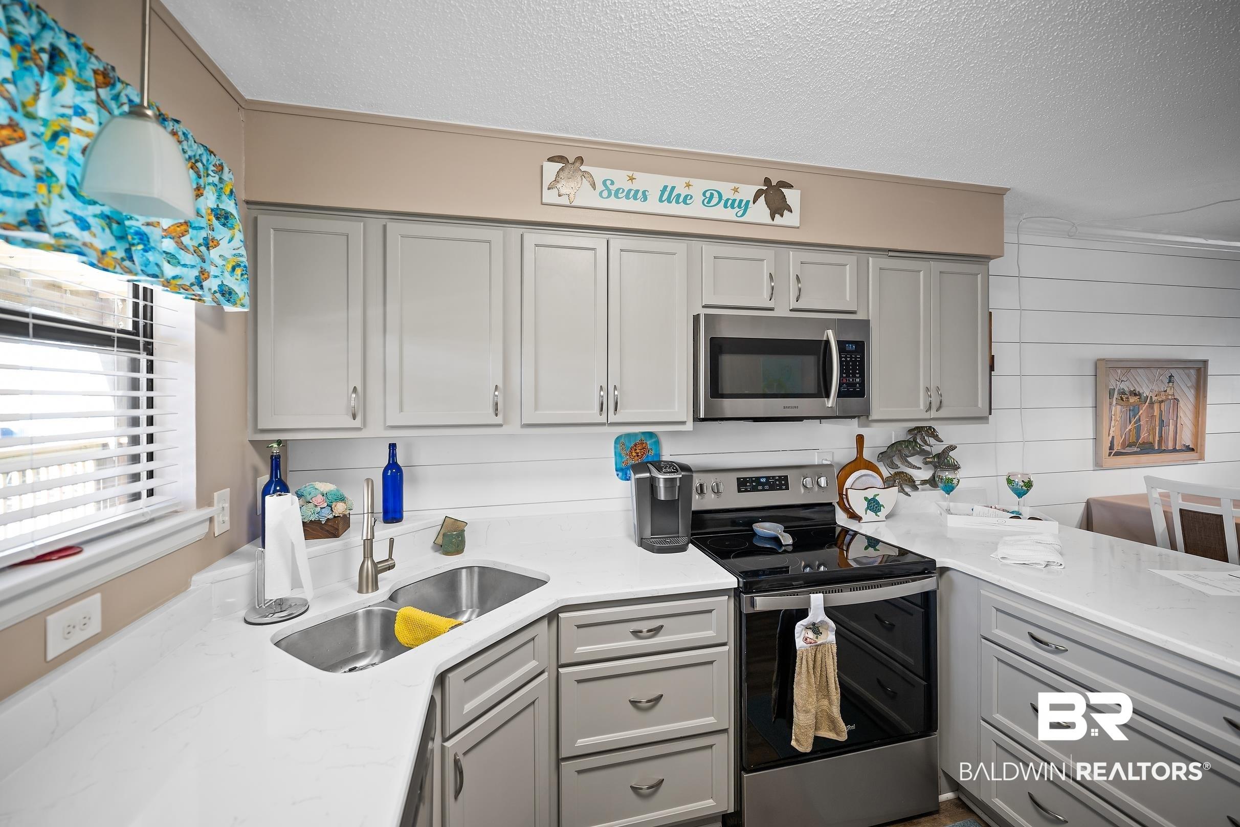 Image 3: Kitchen featuring stainless steel appliances, light stone counters, gray cabinets, and a textured ceiling