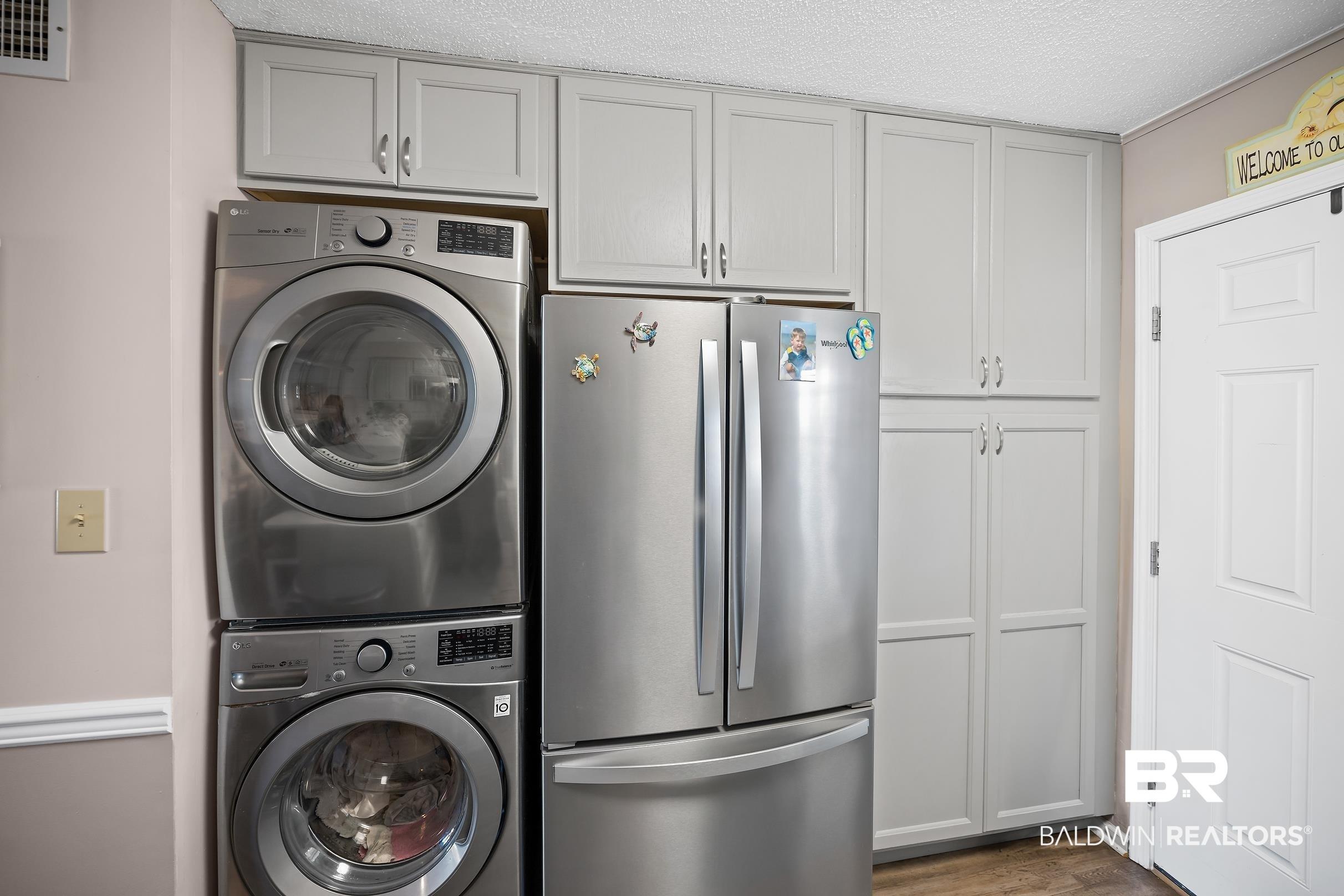 Image 4: Laundry area with stacked washer / dryer, a textured ceiling, and dark wood-style floors