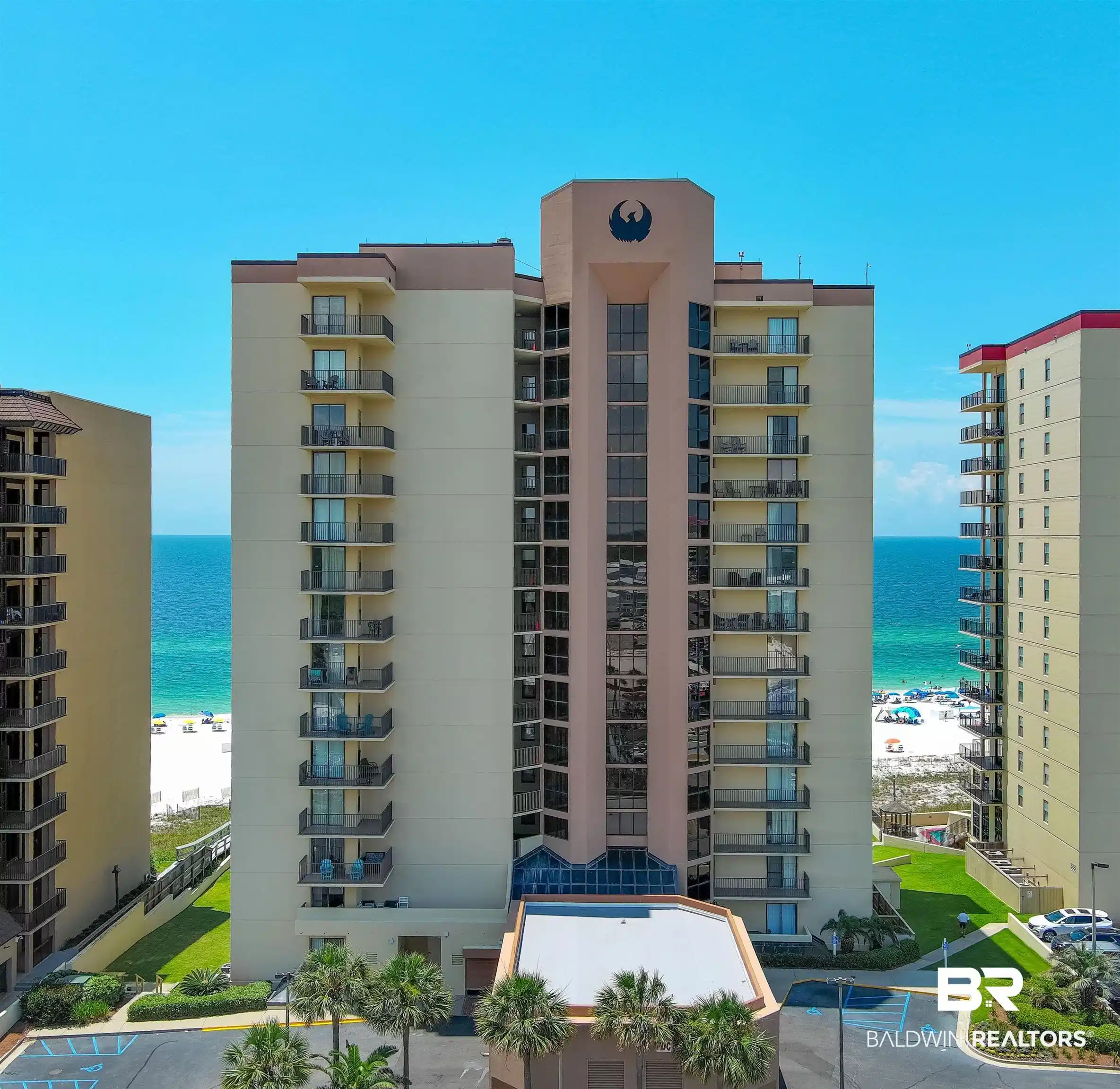 Image 1: Multi-story building featuring individual balconies, a prominent central architectural design, and a direct beachfront setting