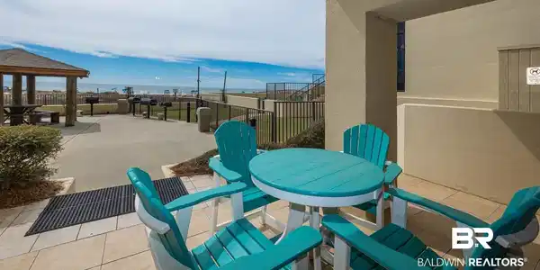 Image 4: Outdoor patio with tile flooring, offering direct access to an expansive concrete common area