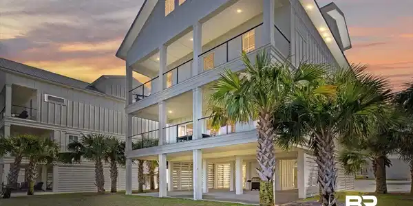 Image 2: Board and batten exterior with multiple levels of covered balconies featuring glass panel railings, recessed lighting, and a ground-level covered patio