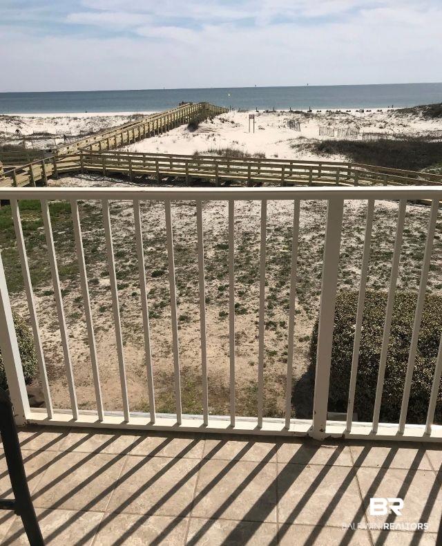 Image 2: Balcony with tiled flooring and a white metal railing overlooking a sandy beach with wooden boardwalks