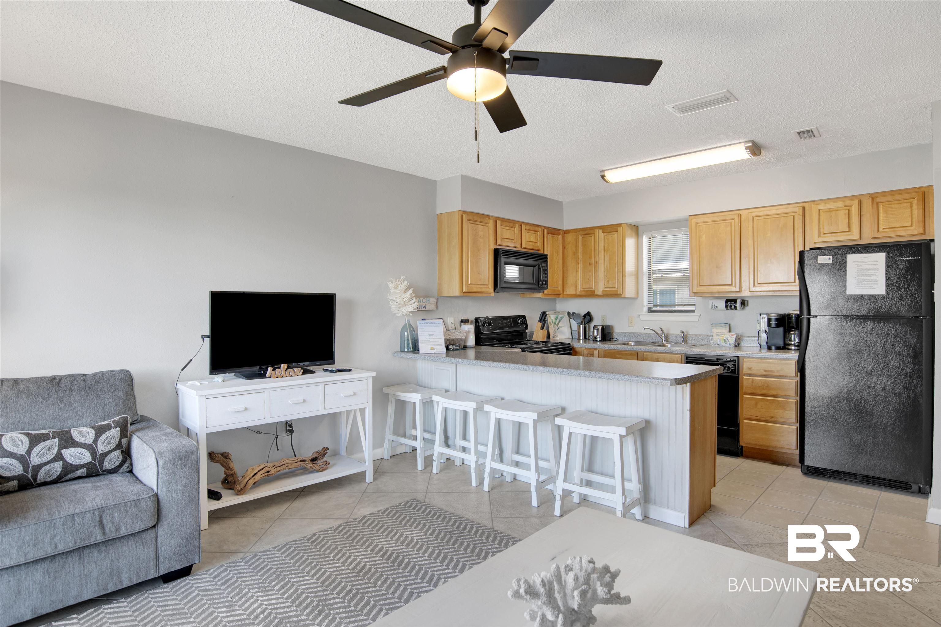 Image 2: Kitchen with black appliances, open floor plan, light tile patterned floors, a kitchen bar, and a textured ceiling