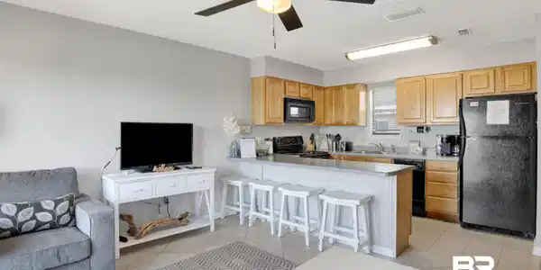 Image 2: Kitchen with black appliances, open floor plan, light tile patterned floors, a kitchen bar, and a textured ceiling