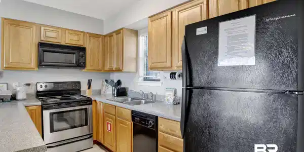 Image 4: Kitchen with black appliances, light countertops, a textured ceiling, light tile patterned floors, and light brown cabinetry