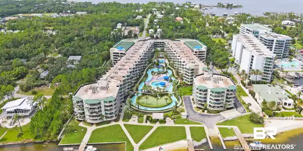 Image 3: Extensive resort-style property featuring multiple buildings, lush green landscaping, and a large central water park with slides and multiple pools