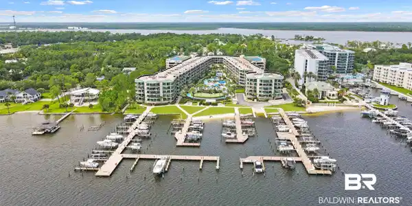 Image 4: Expansive waterfront property featuring multiple residential buildings, private docks with numerous boat slips, a sandy shoreline, and a substantial green space