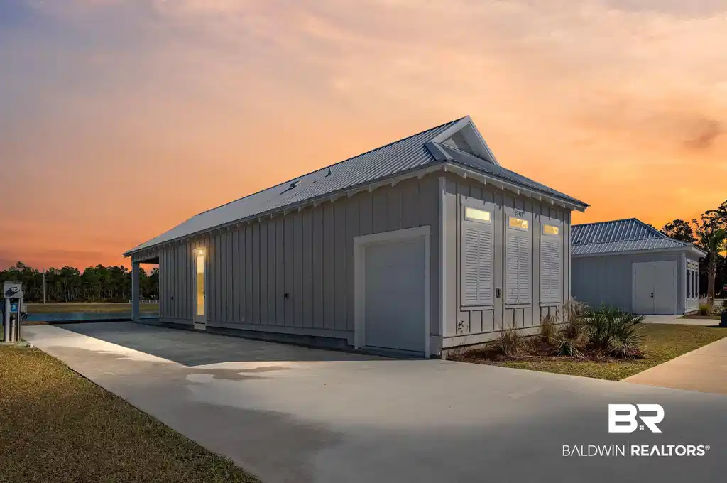 Image 1: Property exterior at dusk with a metal roof, a garage, an outbuilding, concrete driveway, and board and batten siding