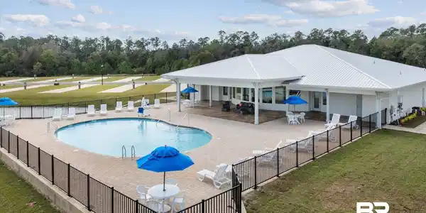 Image 2: Community pool with a patio area and view of wooded area
