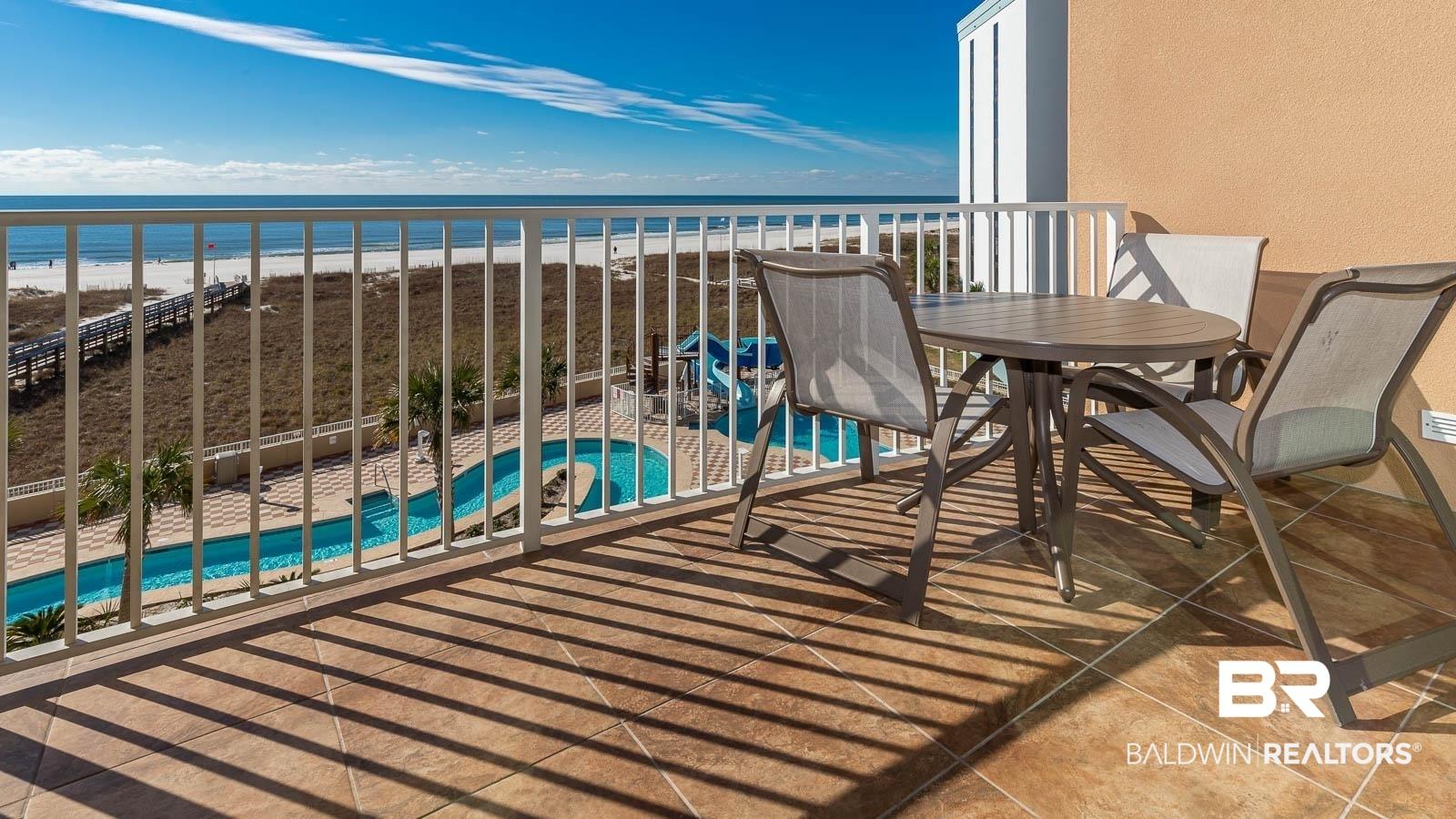 Image 3: Balcony featuring view of pool area, view of water and beach, and outdoor dining space