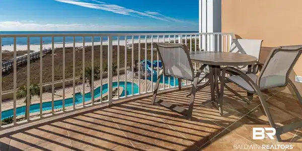 Image 3: Balcony featuring view of pool area, view of water and beach, and outdoor dining space
