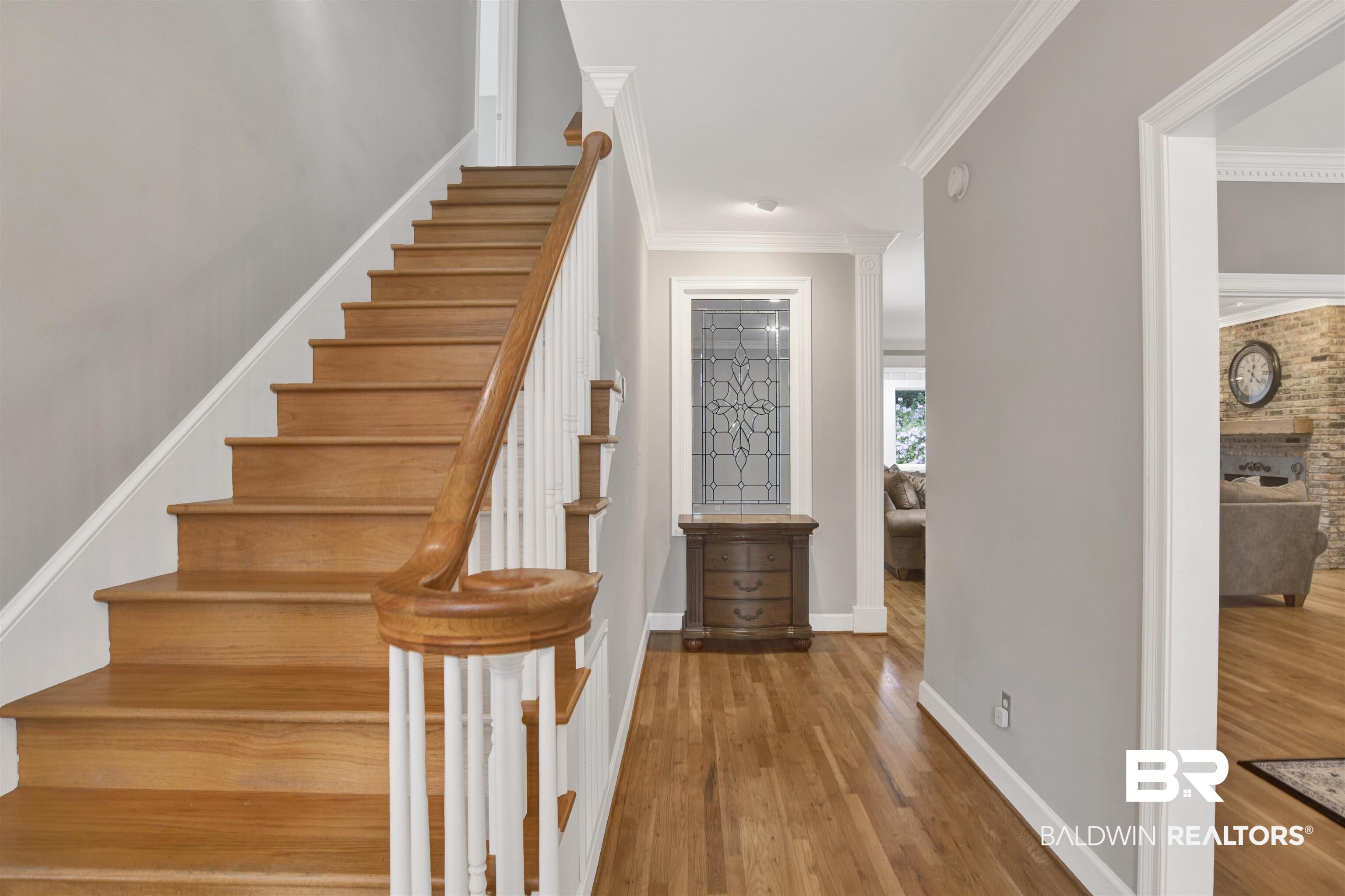 Image 4: Stairs with wood finished floors, crown molding, and a brick fireplace