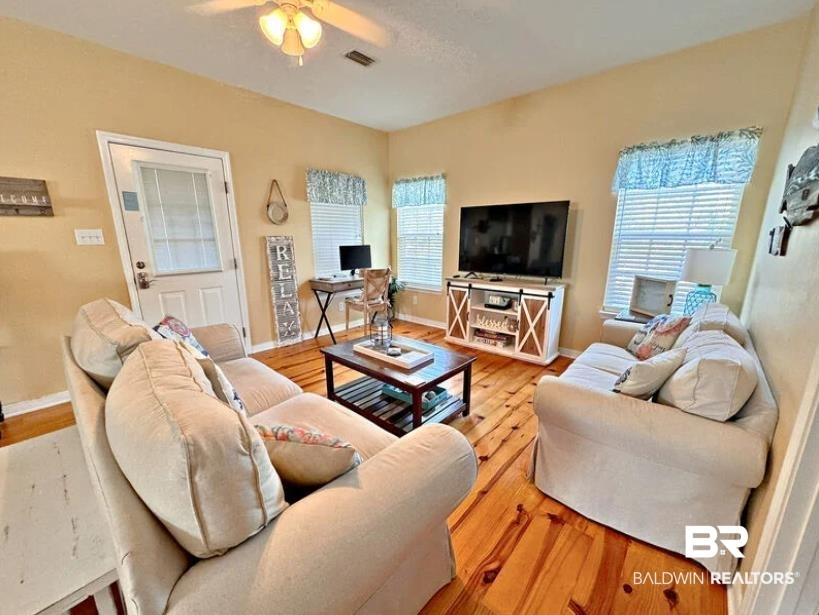 Image 2: Living area with wood-finish flooring, light yellow walls, and multiple windows