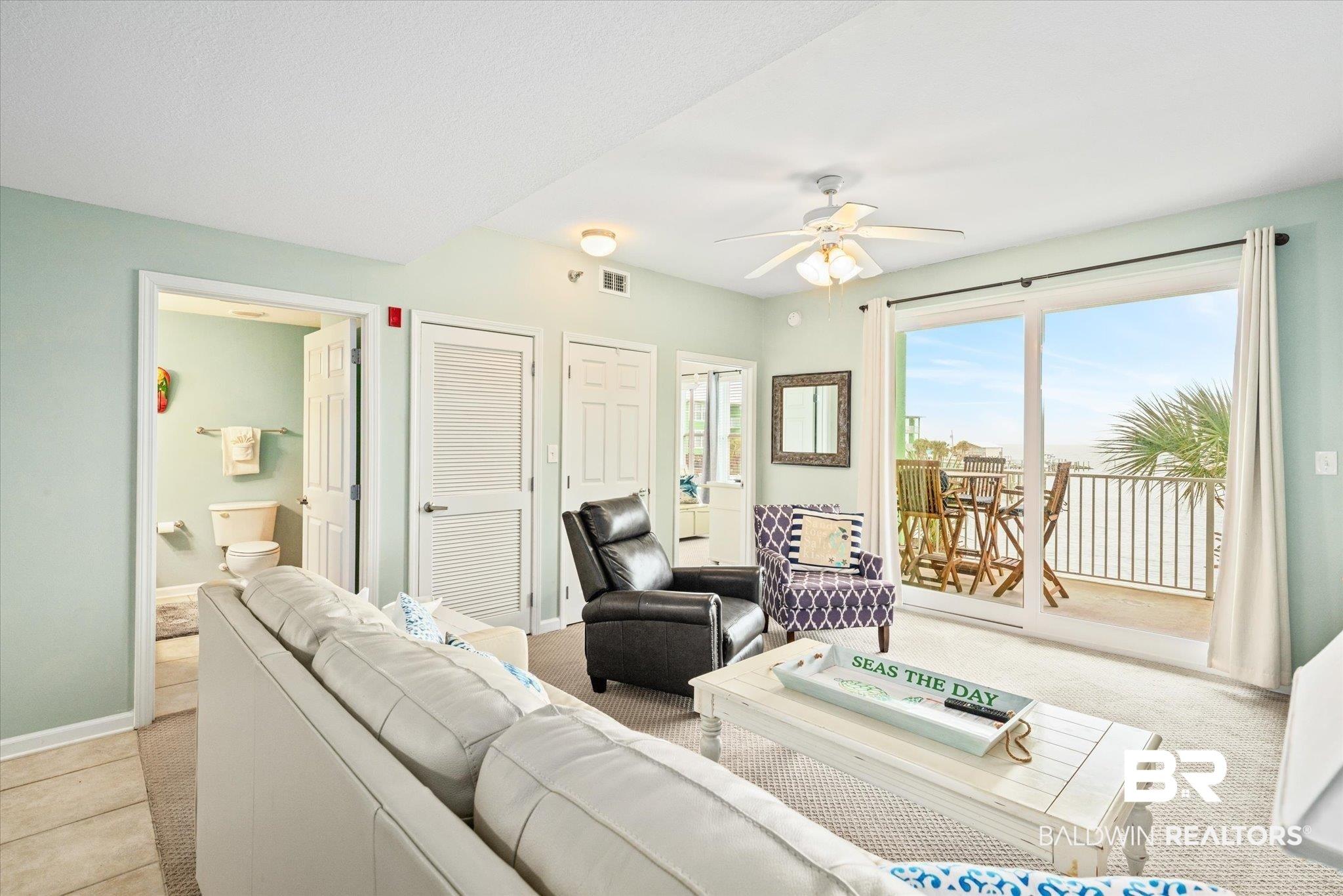 Image 2: Living area with light colored carpet and a ceiling fan