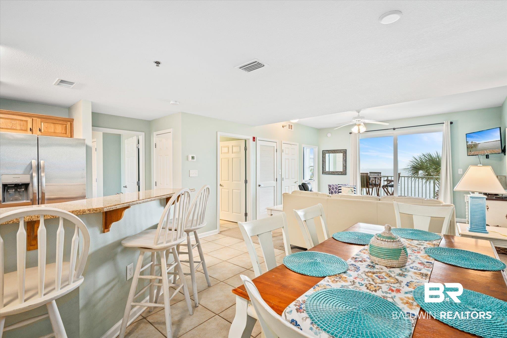Image 4: Dining area with light tile patterned floors and ceiling fan