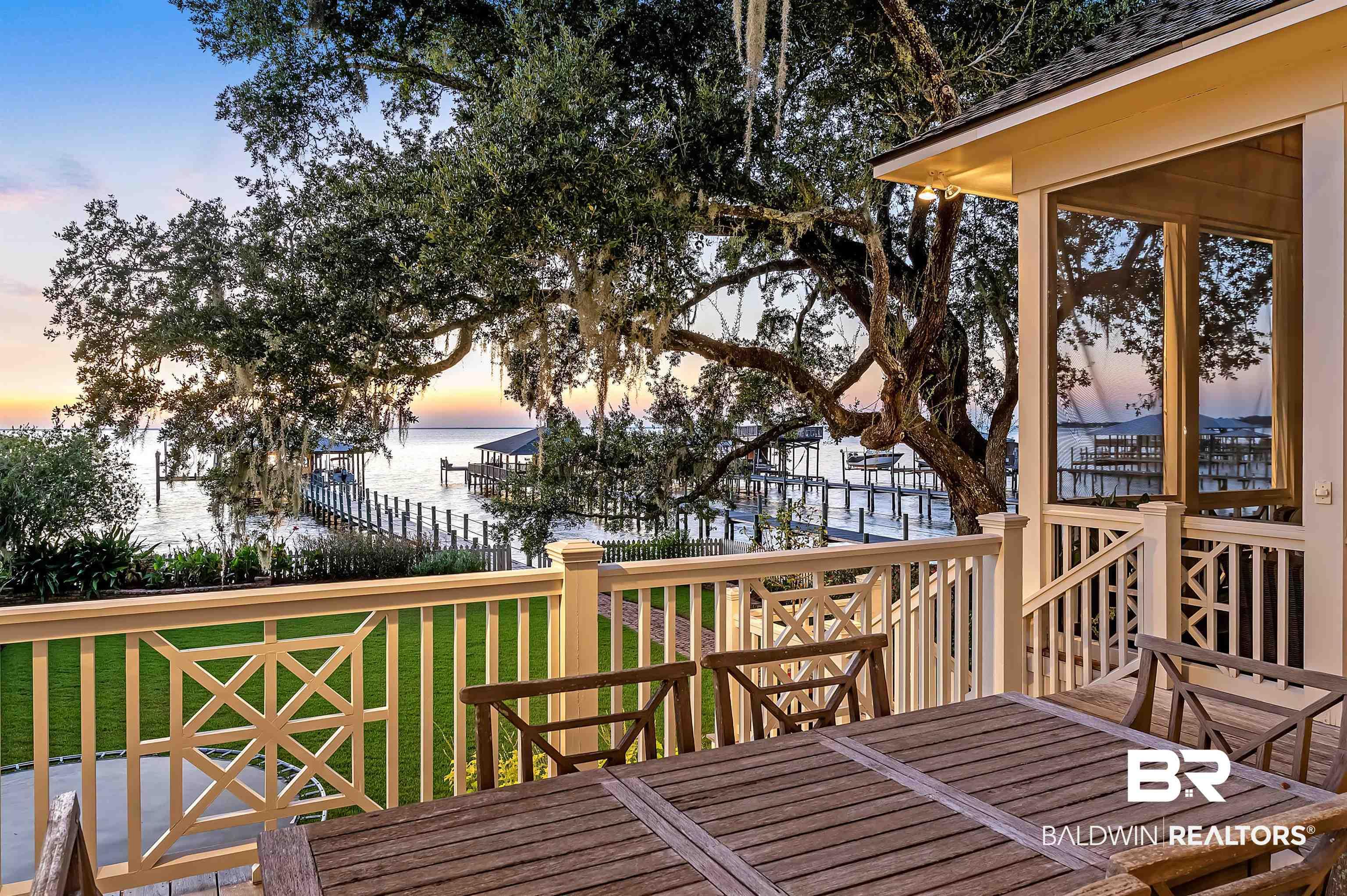Image 3: Deck at dusk featuring a water view, a yard, and outdoor dining area