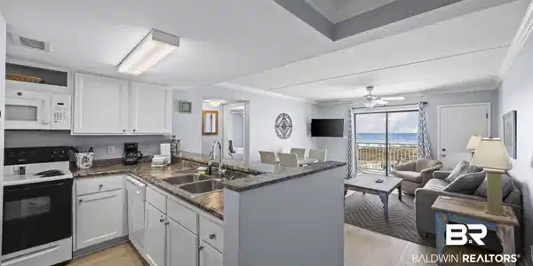 Image 2: Kitchen featuring white appliances, crown molding, light wood-type flooring, a peninsula, and white cabinetry