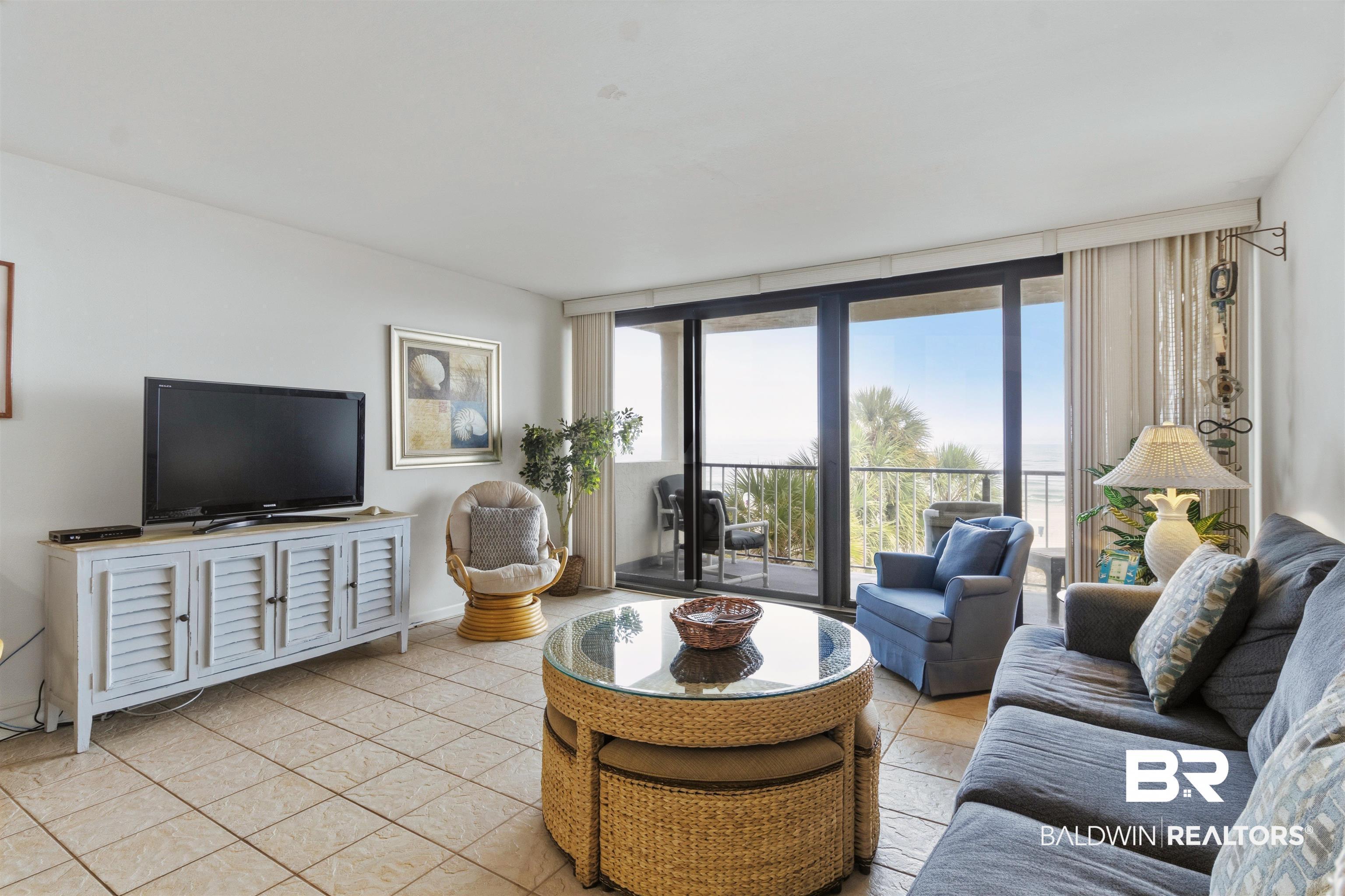 Image 3: Living area featuring tile flooring, white walls, and a built-in media console with louvered doors