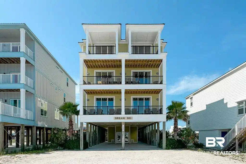 Image 1: Four-story coastal residence featuring multiple balconies and a ground-level covered parking area