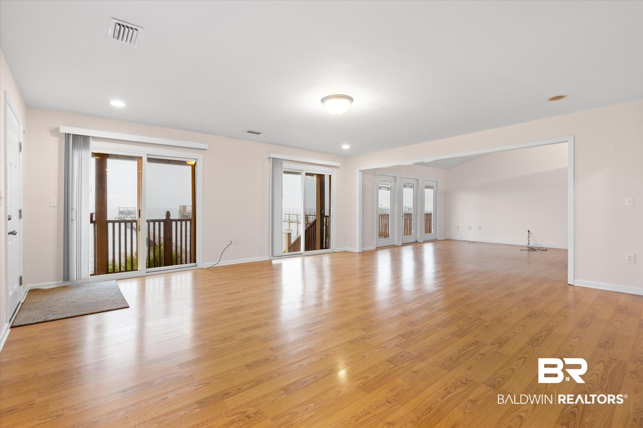 Image 4: Unfurnished living room featuring baseboards, light wood-style flooring, a wealth of natural light, and visible vents