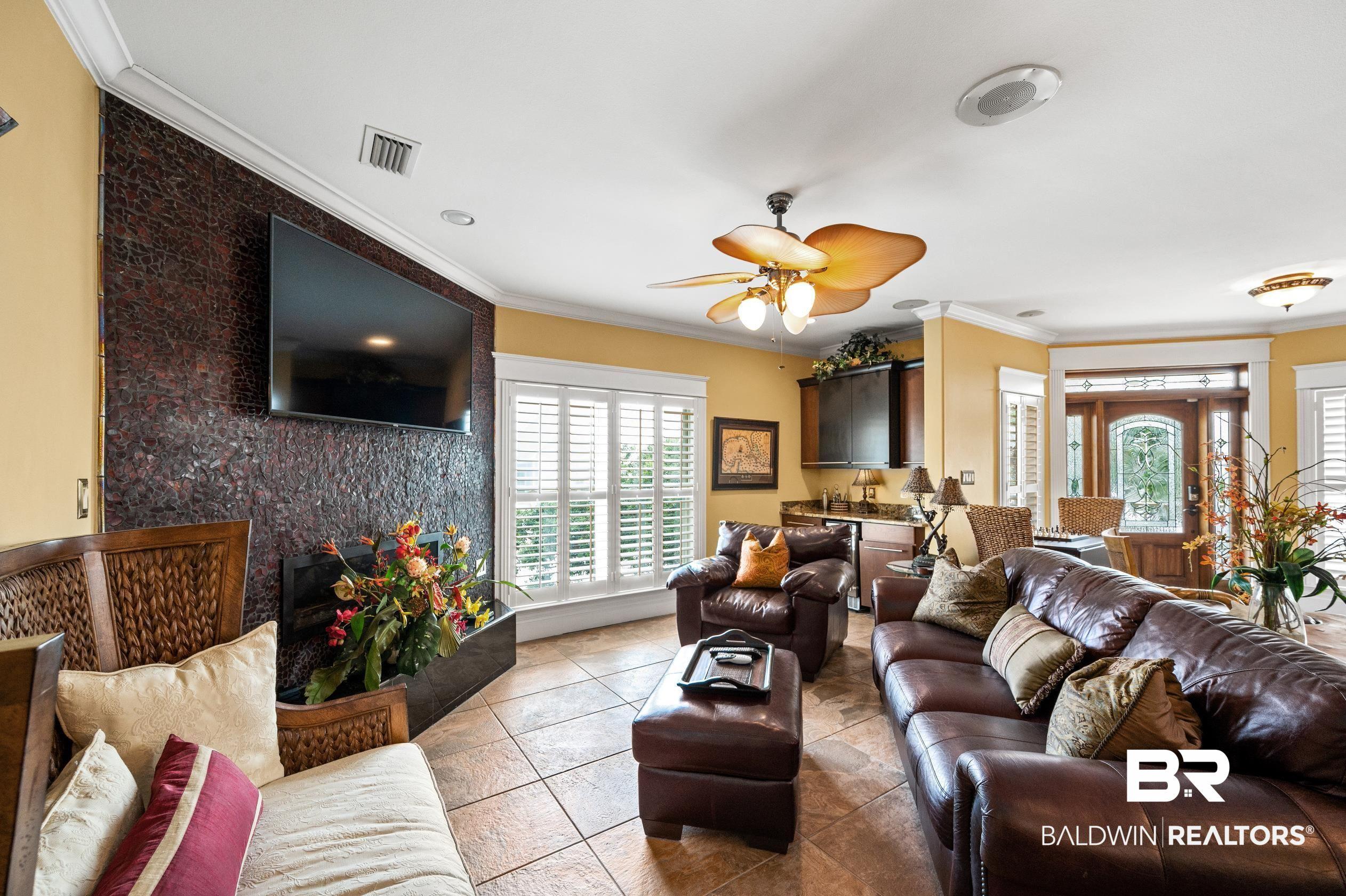 Image 4: Living area featuring crown molding, healthy amount of natural light, ceiling fan, and light tile patterned flooring