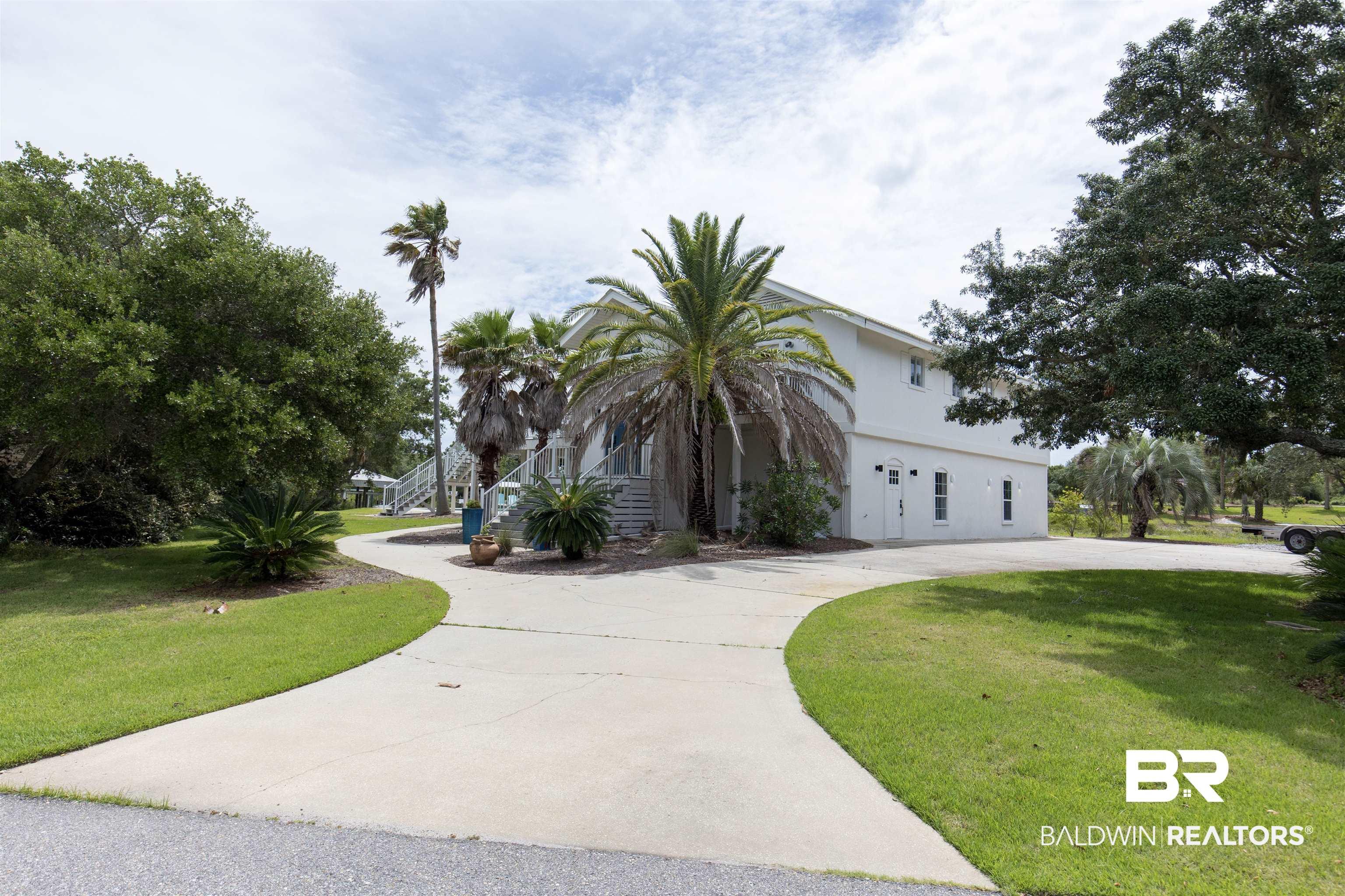 Image 2: White two-story exterior with multiple windows and doors, set against a backdrop of mature trees and tropical landscaping