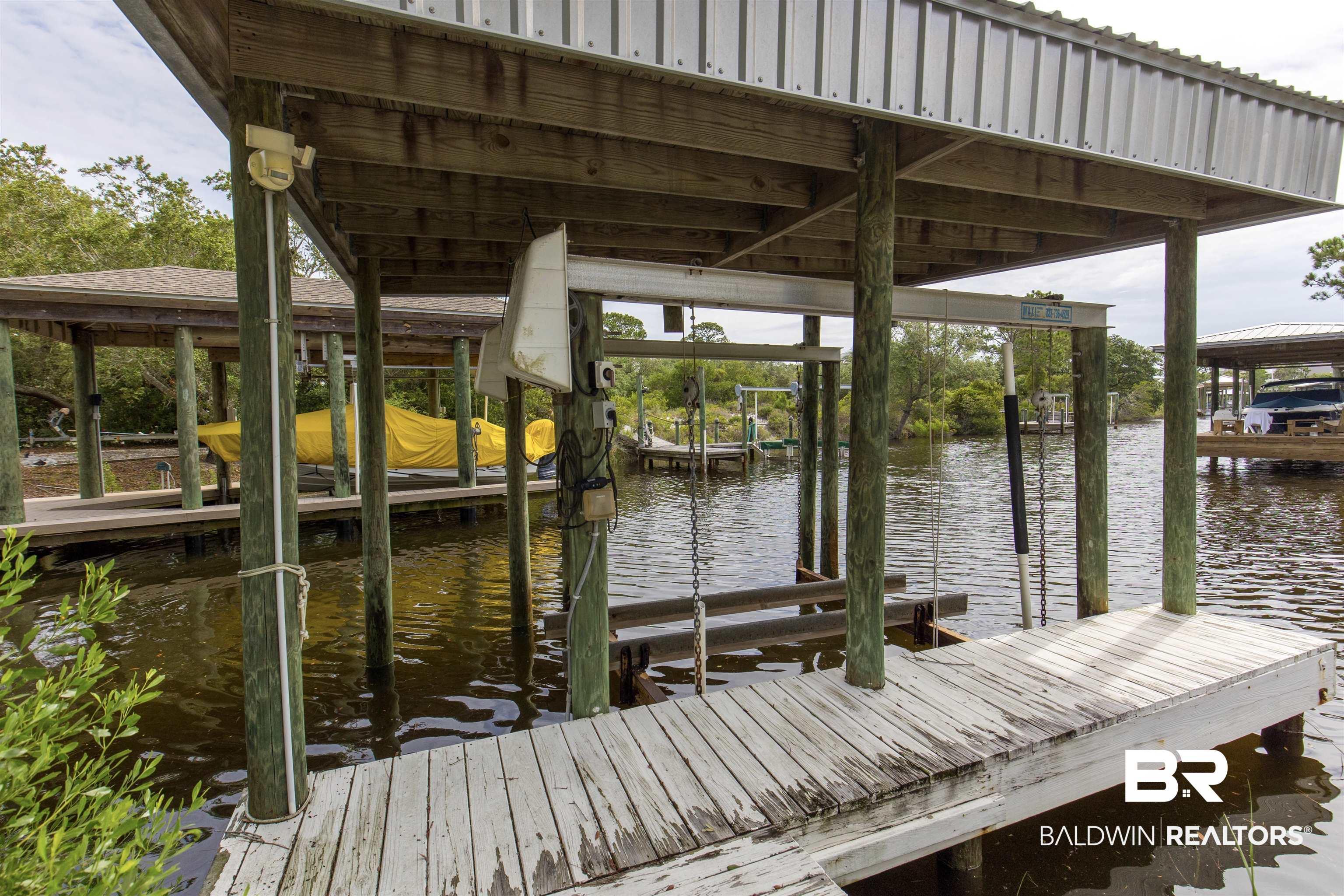 Image 4: Covered boat dock featuring a metal roof, wood pilings, and a built-in boat lift system