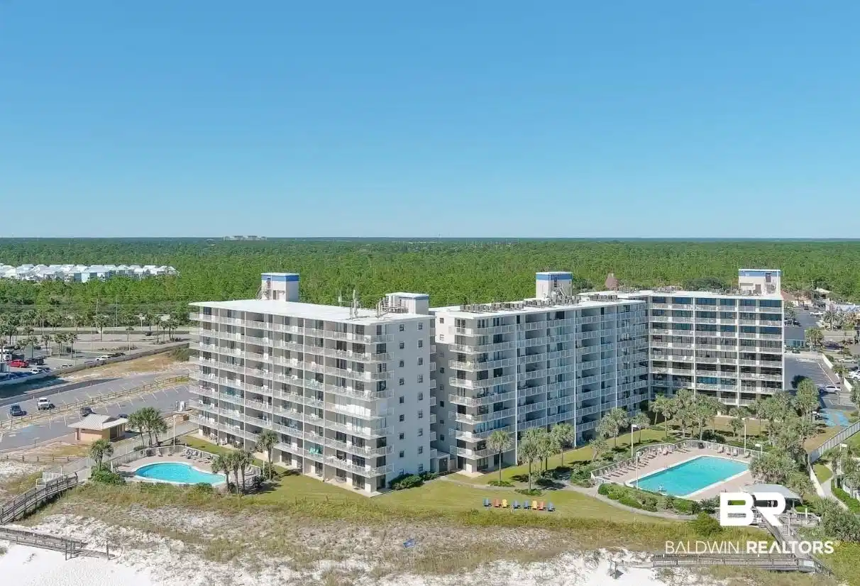 Image 1: Beachfront condominium complex featuring multiple swimming pools, extensive patio areas, direct beach access via wooden boardwalks, and a backdrop of dense green foliage