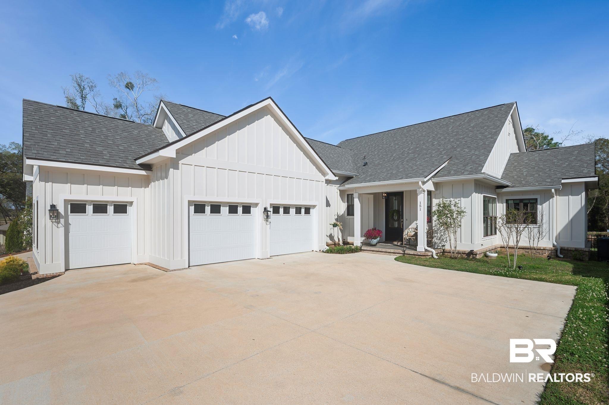 Image 3: Modern farmhouse style home with a shingled roof, board and batten siding, 2 car and a golf cart/sedan garage too.