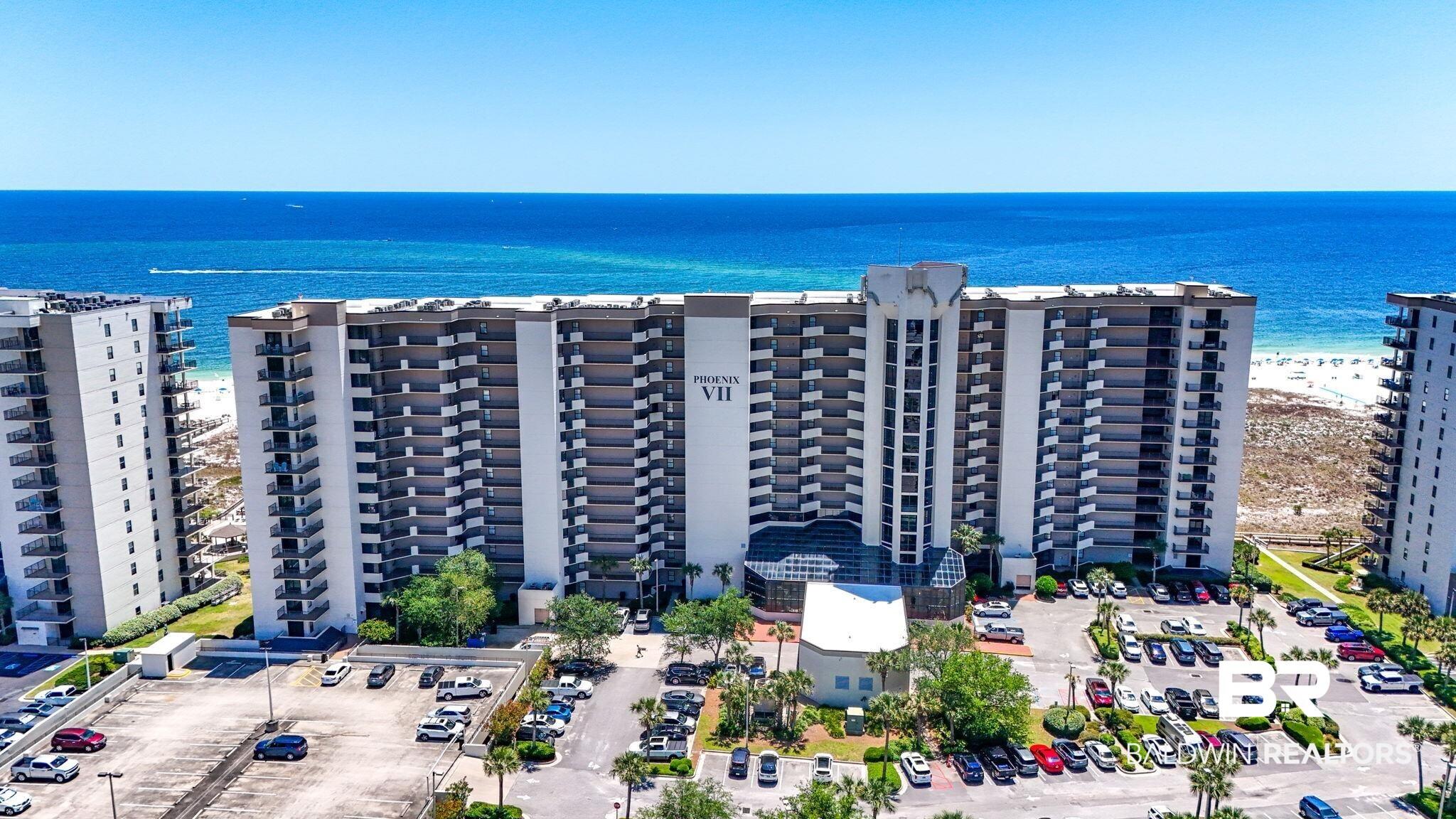 Image 2: High-rise coastal condominium building featuring multiple private balconies, a direct beachfront location, and a large parking area