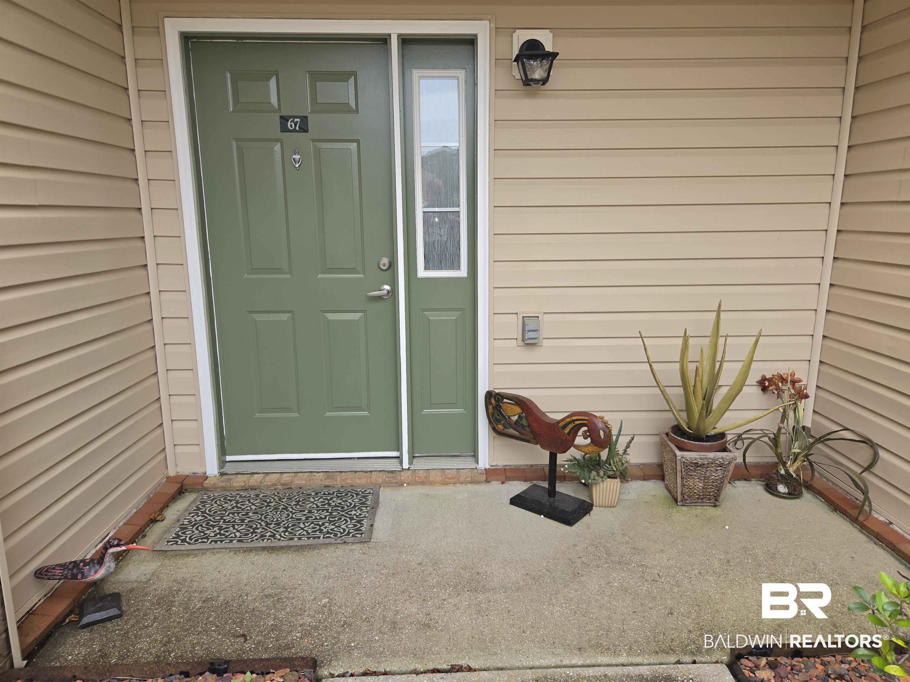 Image 4: Entryway featuring a paneled green door with a sidelight, an exterior wall lantern, and horizontal siding