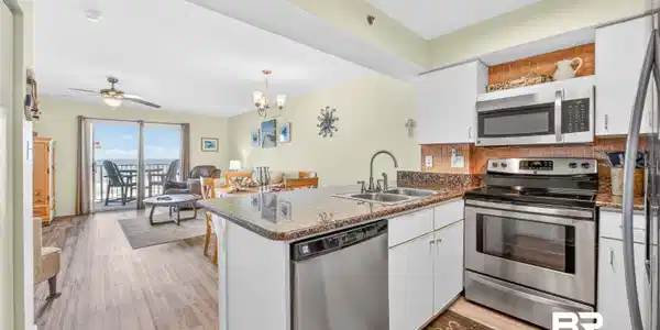 Image 2: Open-concept kitchen featuring white cabinetry, stainless steel appliances, granite countertops, and a tile backsplash