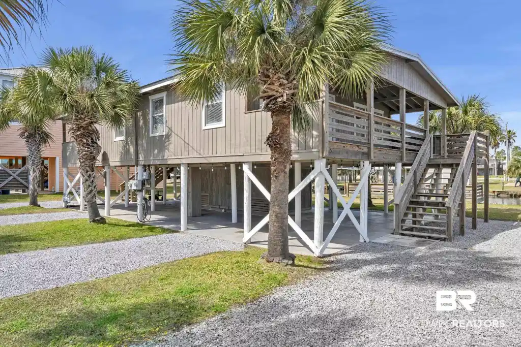 Image 1: Elevated coastal residence featuring a covered front porch, exterior staircase, and ground-level parking