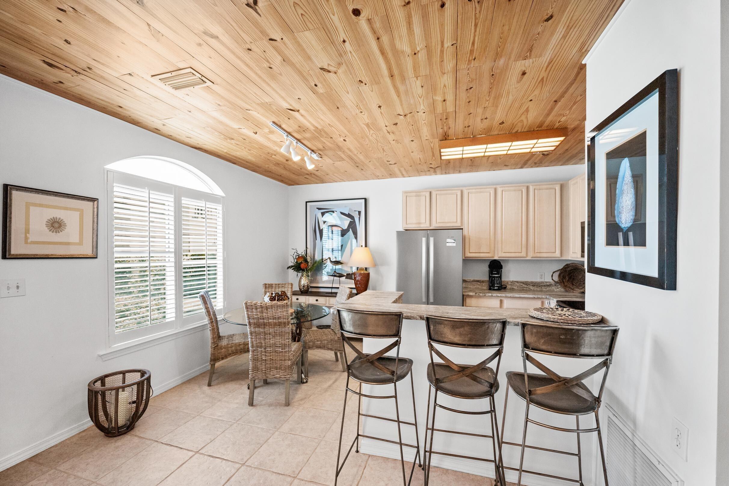 Image 2: Kitchen with a peninsula, freestanding refrigerator, a breakfast bar, light tile patterned floors, and wood ceiling