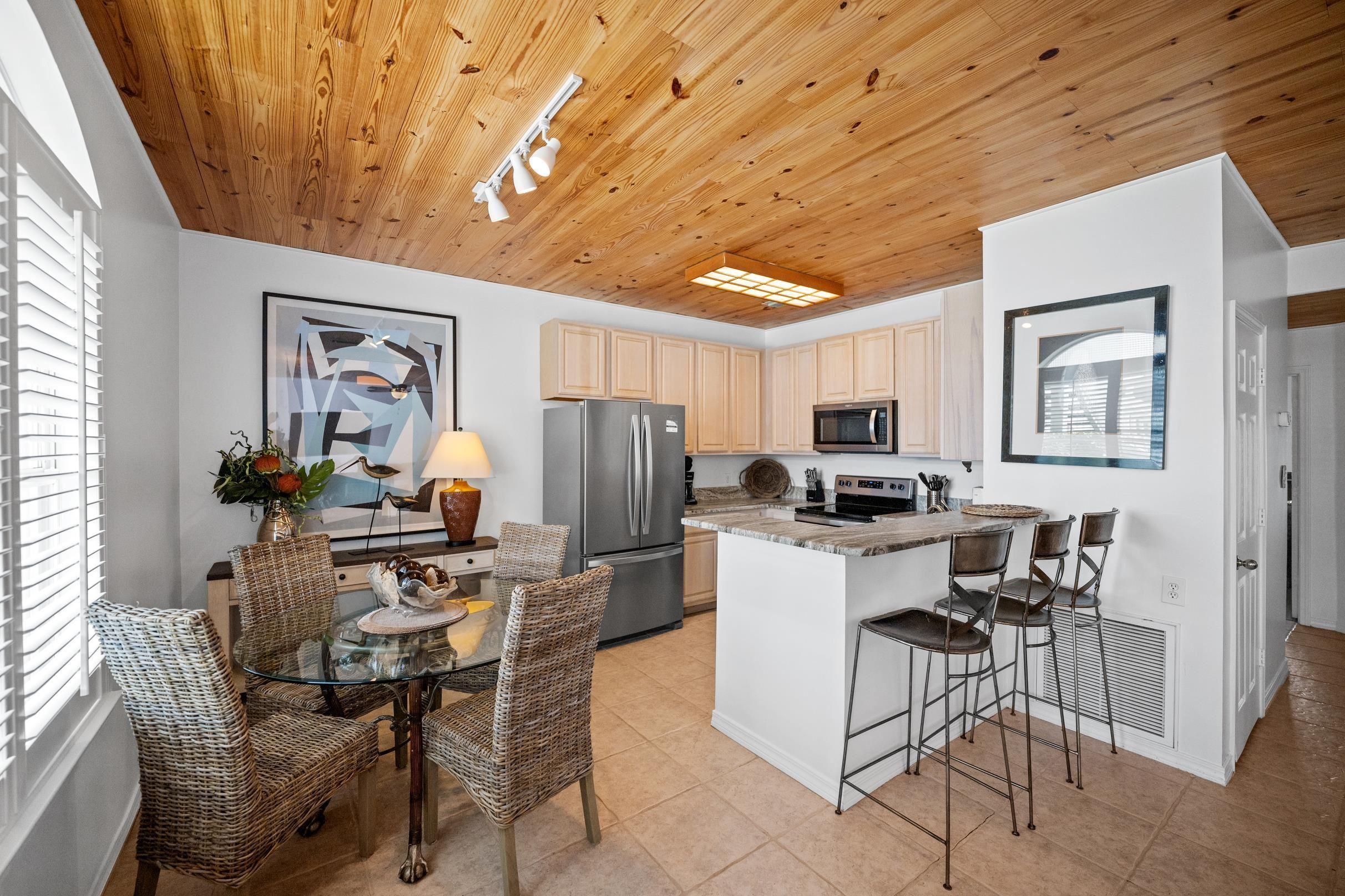 Image 3: Kitchen featuring a peninsula, appliances with stainless steel finishes, a kitchen breakfast bar, light tile patterned floors, and light brown cabinetry
