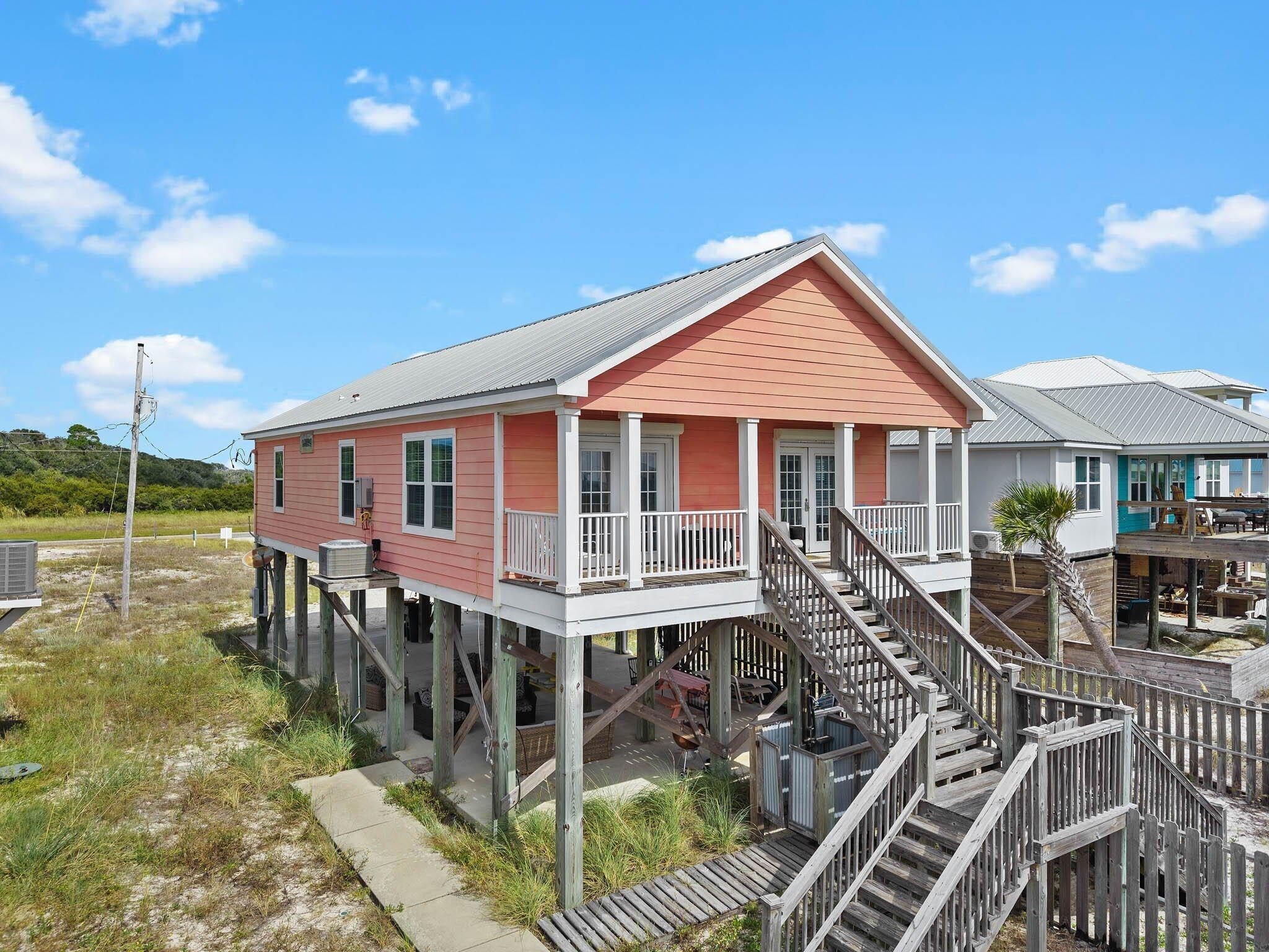 Image 1: Coastal inspired home with a metal roof, stairs, and french doors