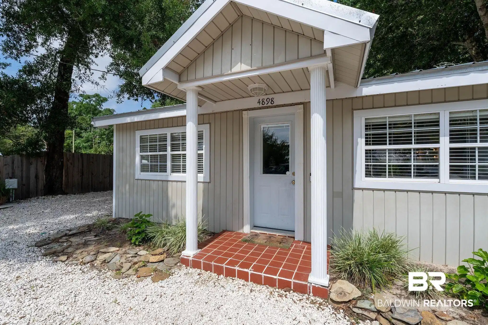 Image 1: Entryway featuring a covered porch with white columns, red tile flooring, and a glass-paneled door