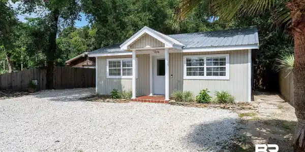 Image 2: Single-story residence featuring a gray metal roof and light-colored vertical siding