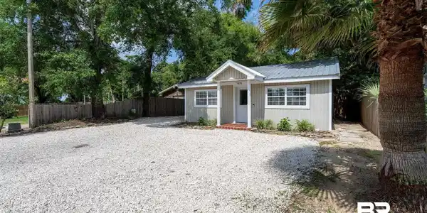 Image 4: Compact exterior featuring a light-colored siding, white-framed windows, and a metal roof