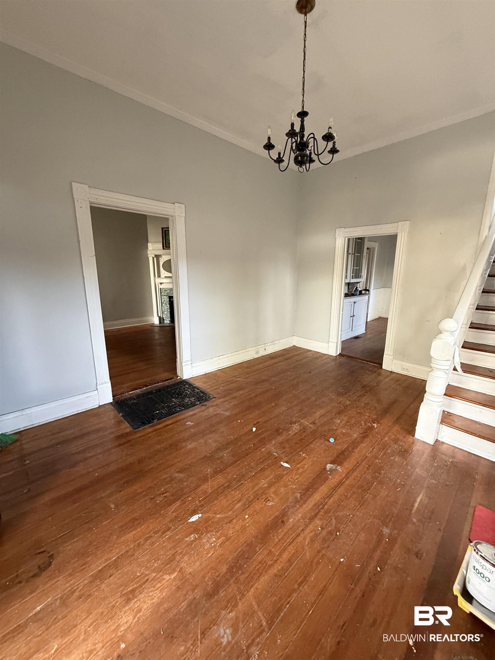 Image 3: Unfurnished dining area featuring dark wood-style floors, hanging lights, and ornamental molding