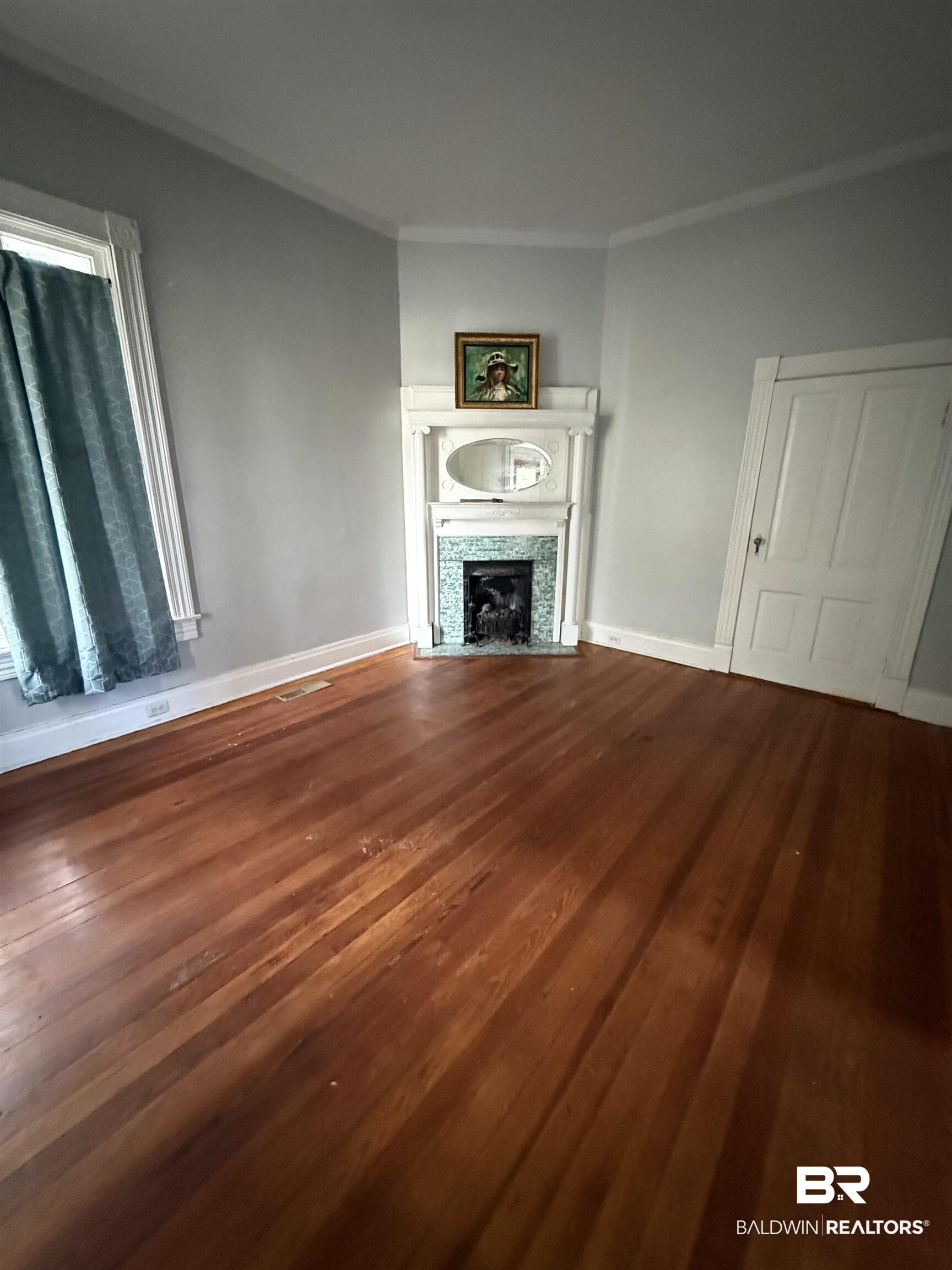 Image 4: Unfurnished living room with dark wood-type flooring, a tile fireplace, and ornamental molding