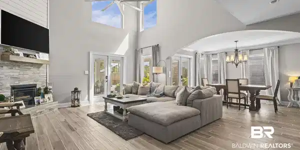 Image 4: Living room featuring arched walkways, a chandelier, ceiling fan, a stone fireplace, and plenty of natural light